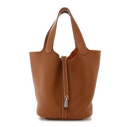 Tan leather tote bag with structured bucket shape and front lock strap