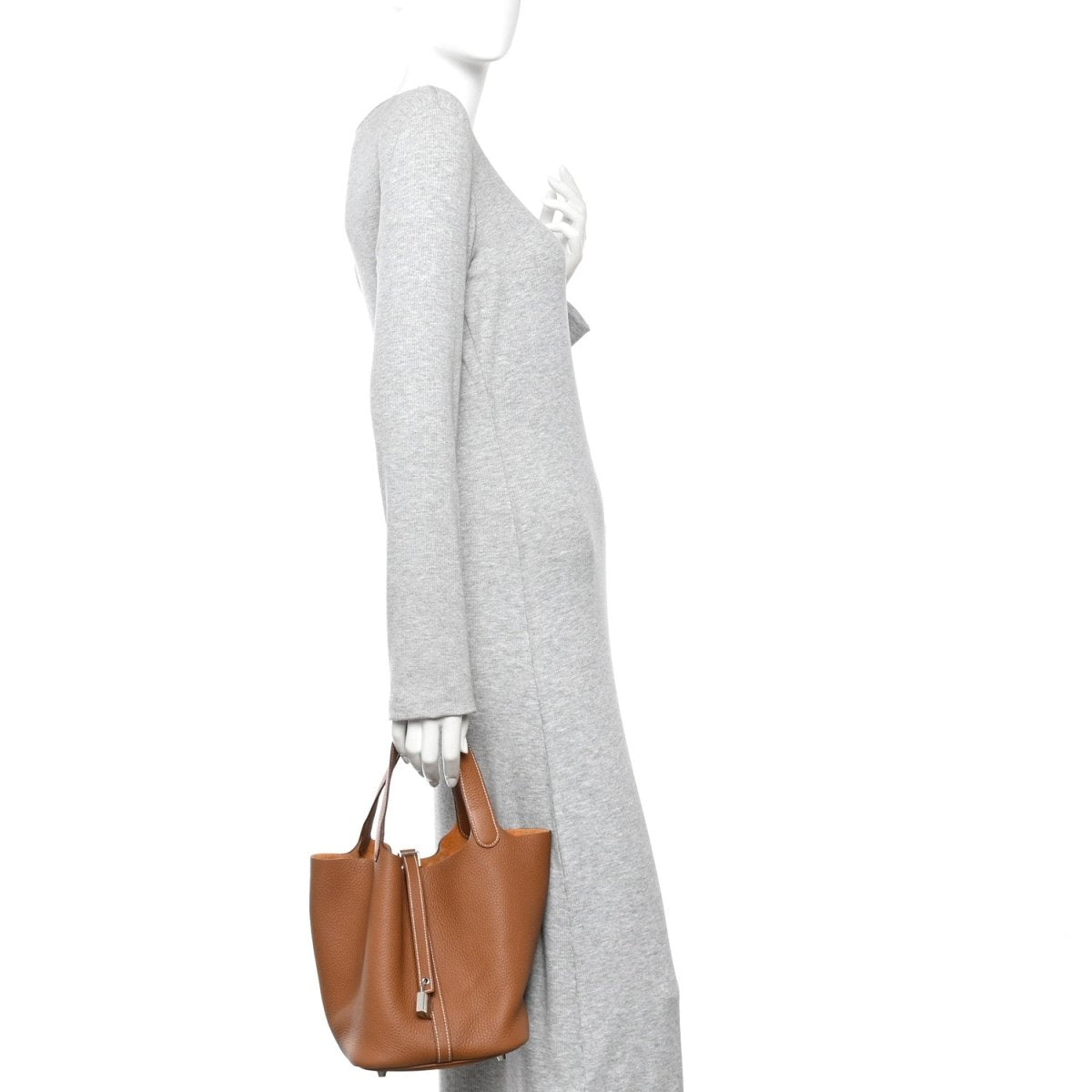 Tan leather tote bag with front lock strap, worn on shoulder