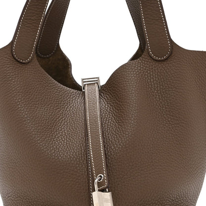 Taupe leather tote bag lock area with metal clasp, zipper track, and stitching