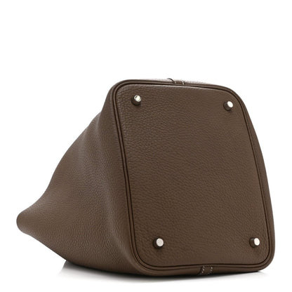 Taupe leather tote bag top panel with four metal studs and curved frame