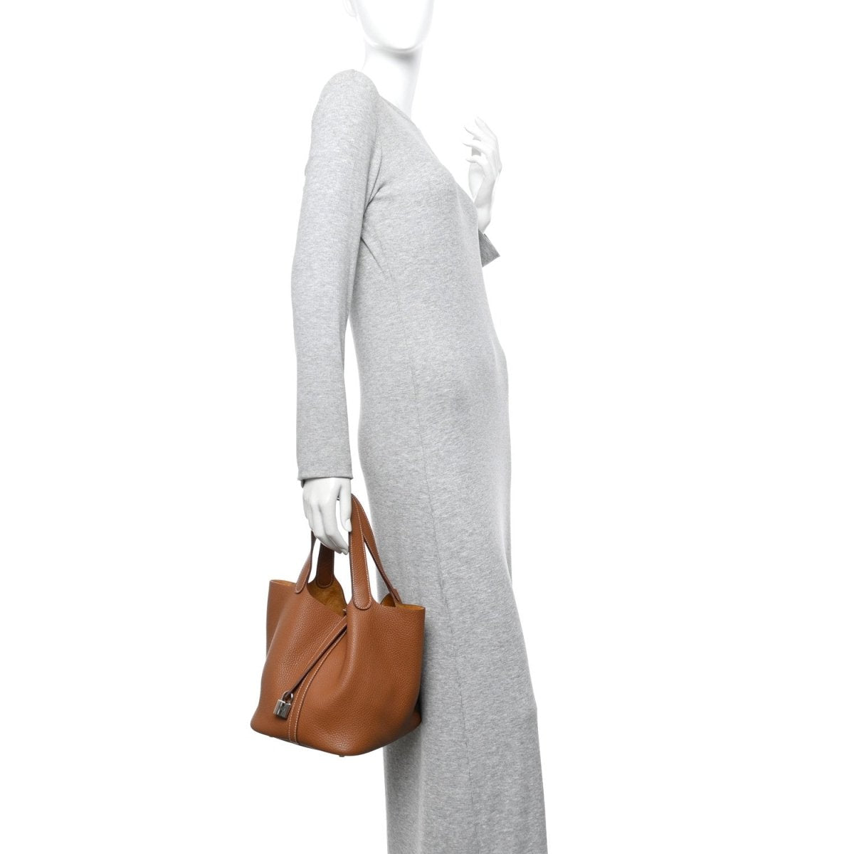 Tan leather tote bag with top handles, carried by a person