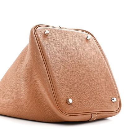 Tan leather tote bag with triangular flap and metal snap studs