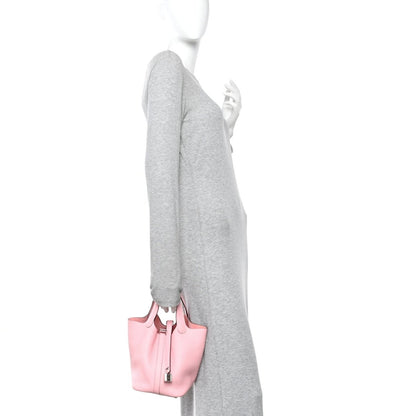 Rose pink leather mini bucket bag with top handles, shown being carried at side