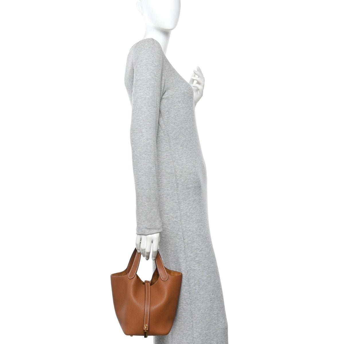 Brown leather Picotin-style mini handbag held by model by top handles