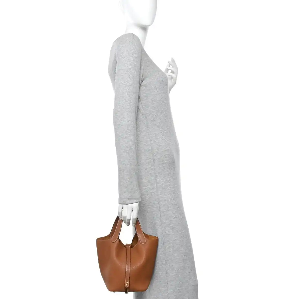 Brown leather Picotin-style mini handbag held by model by top handles