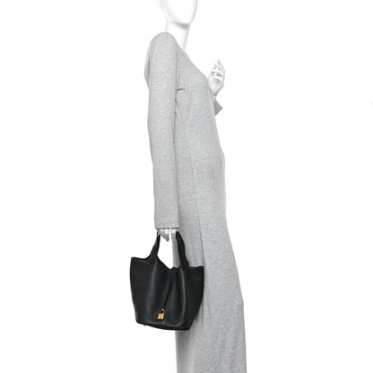 Black leather tote bag worn on shoulder with gold-tone lock at center.