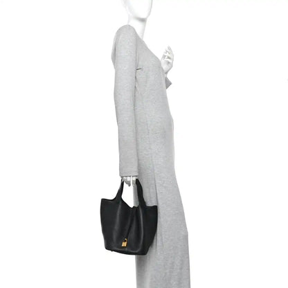 Black leather tote bag worn on shoulder with gold-tone lock at center.