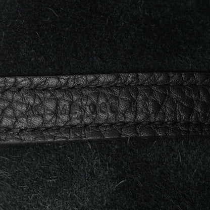 Black leather tote seam detail with pebbled texture and contrast stitching.