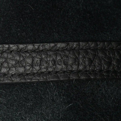 Black leather tote seam detail with pebbled texture and contrast stitching.