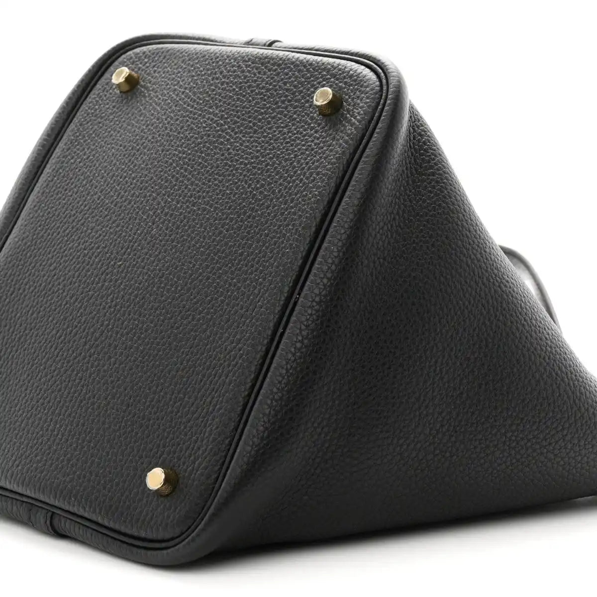 Black leather tote corner with gold-tone studs and angled top panel seam.