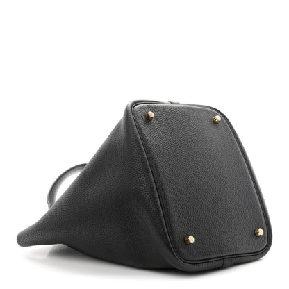 Black leather tote with gold-tone studs and triangular profile on angled view.