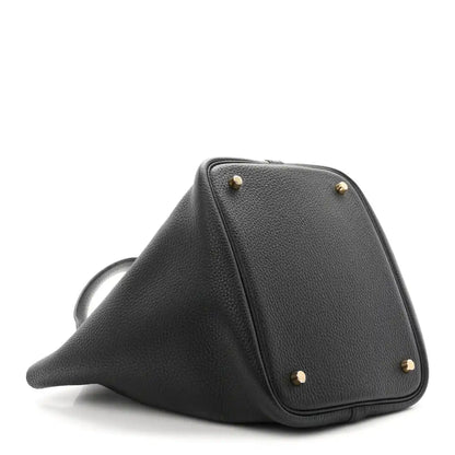 Black leather tote with gold-tone studs and triangular profile on angled view.