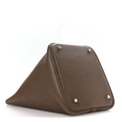 Taupe leather handbag with fold-over top and metal corner feet