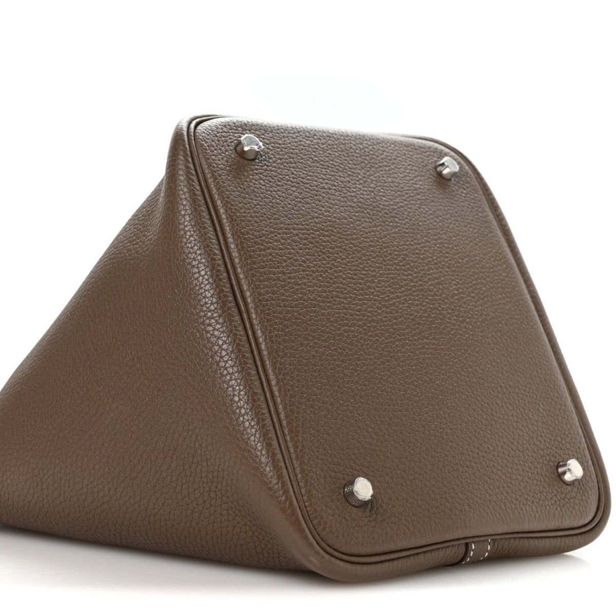 Taupe leather handbag with triangular shape and metal feet on corners