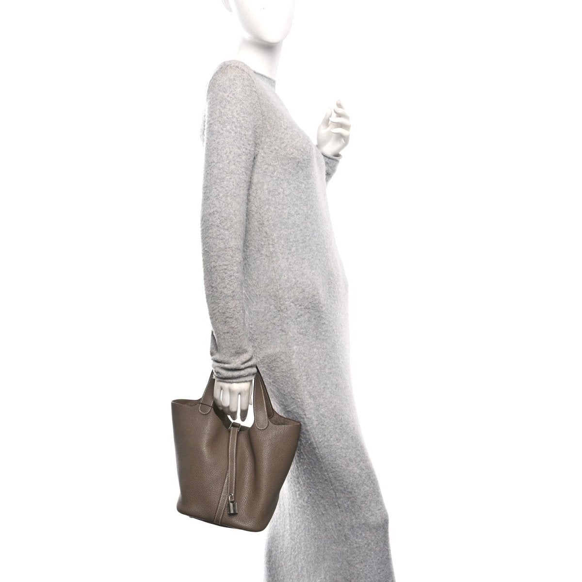 Taupe leather mini handbag on a person’s side, top handles and zipper lock