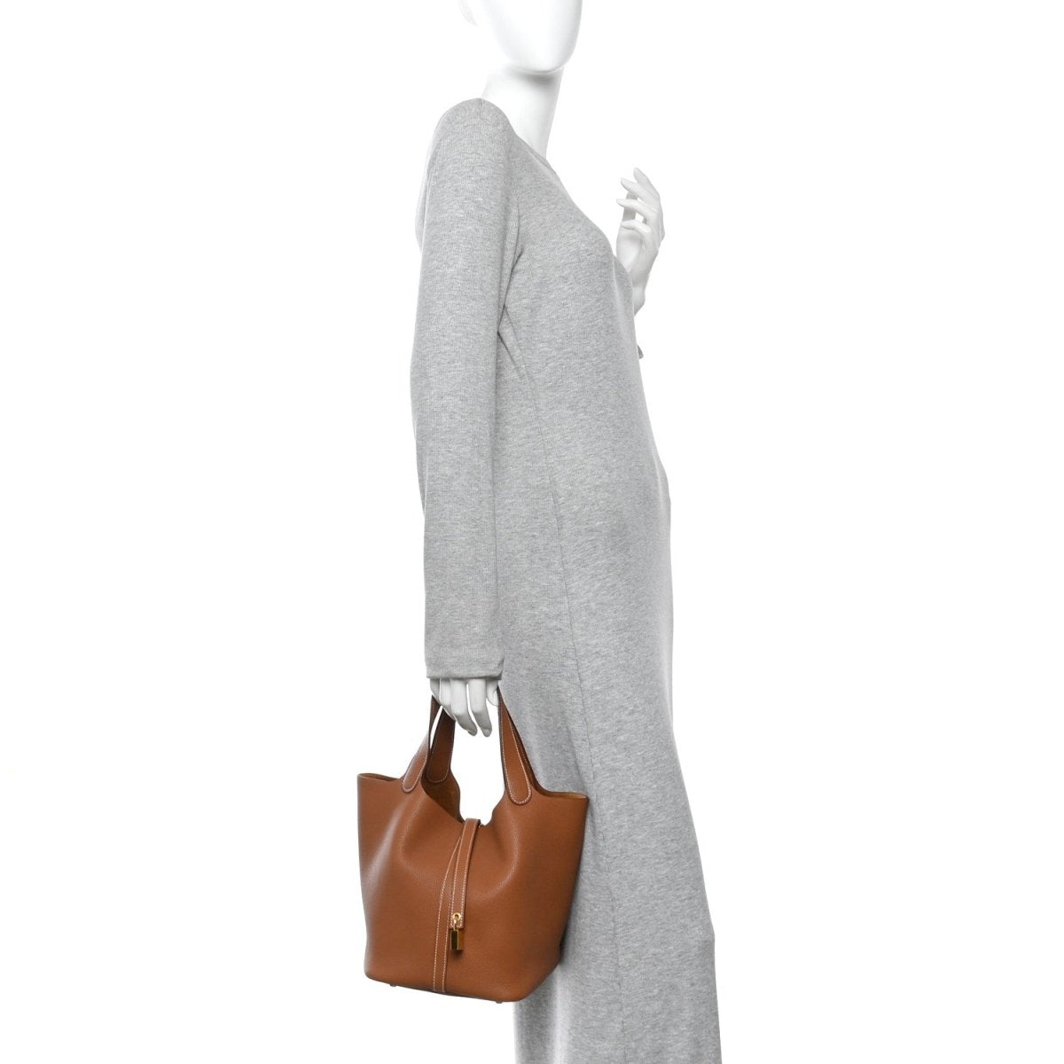 Tan leather tote bag carried at side with gold lock and stitched strap