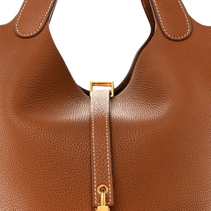 Tan leather tote bag with gold lock clasp and stitched strap detail