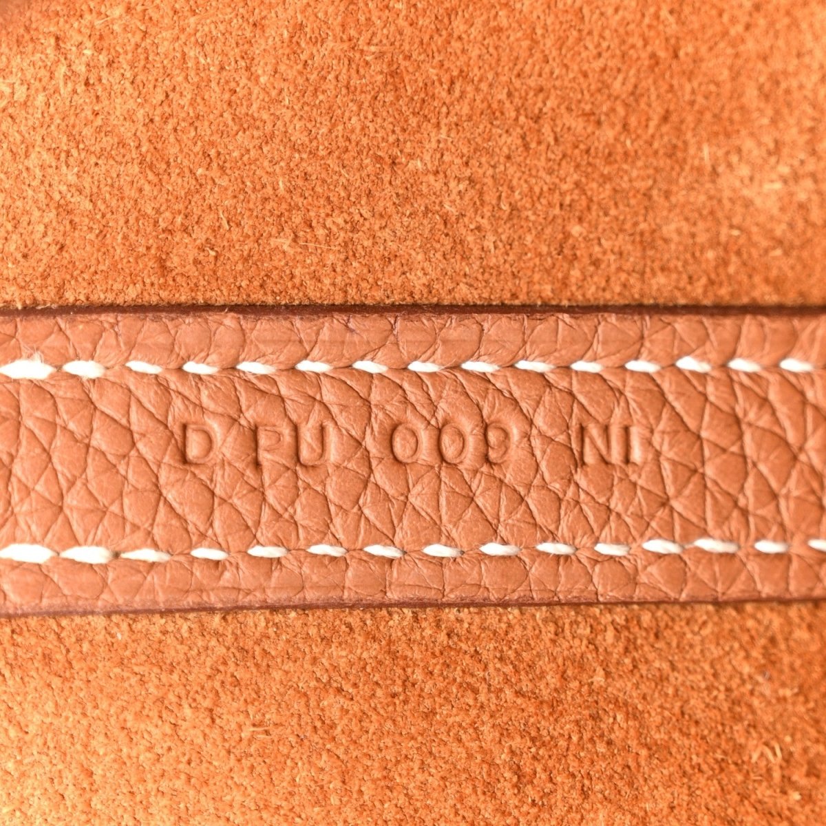 Tan leather tote with quilted texture and white braided edge stitching
