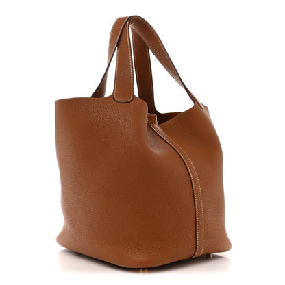 Tan leather tote bag side view with curved silhouette and top handle straps
