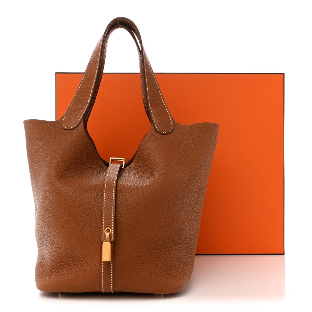 Tan leather tote bag with two rolled handles and gold lock front closure