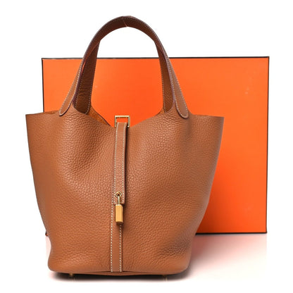 Leather tote bag with top handles and gold lock, tan/brown textured finish.