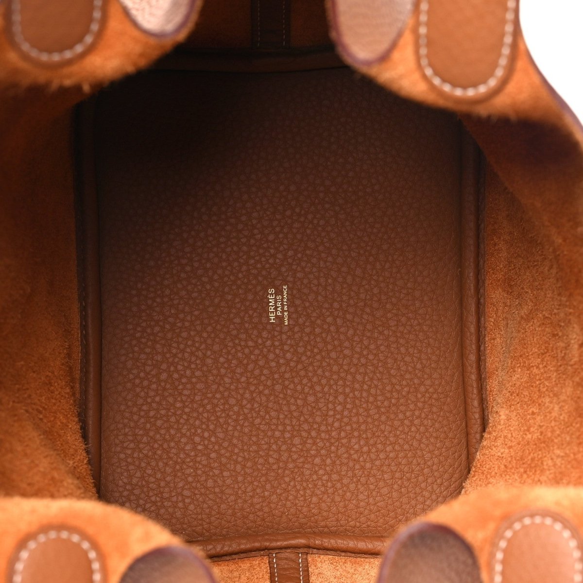 Leather tote interior lining in tan with textured pattern and branding panel.