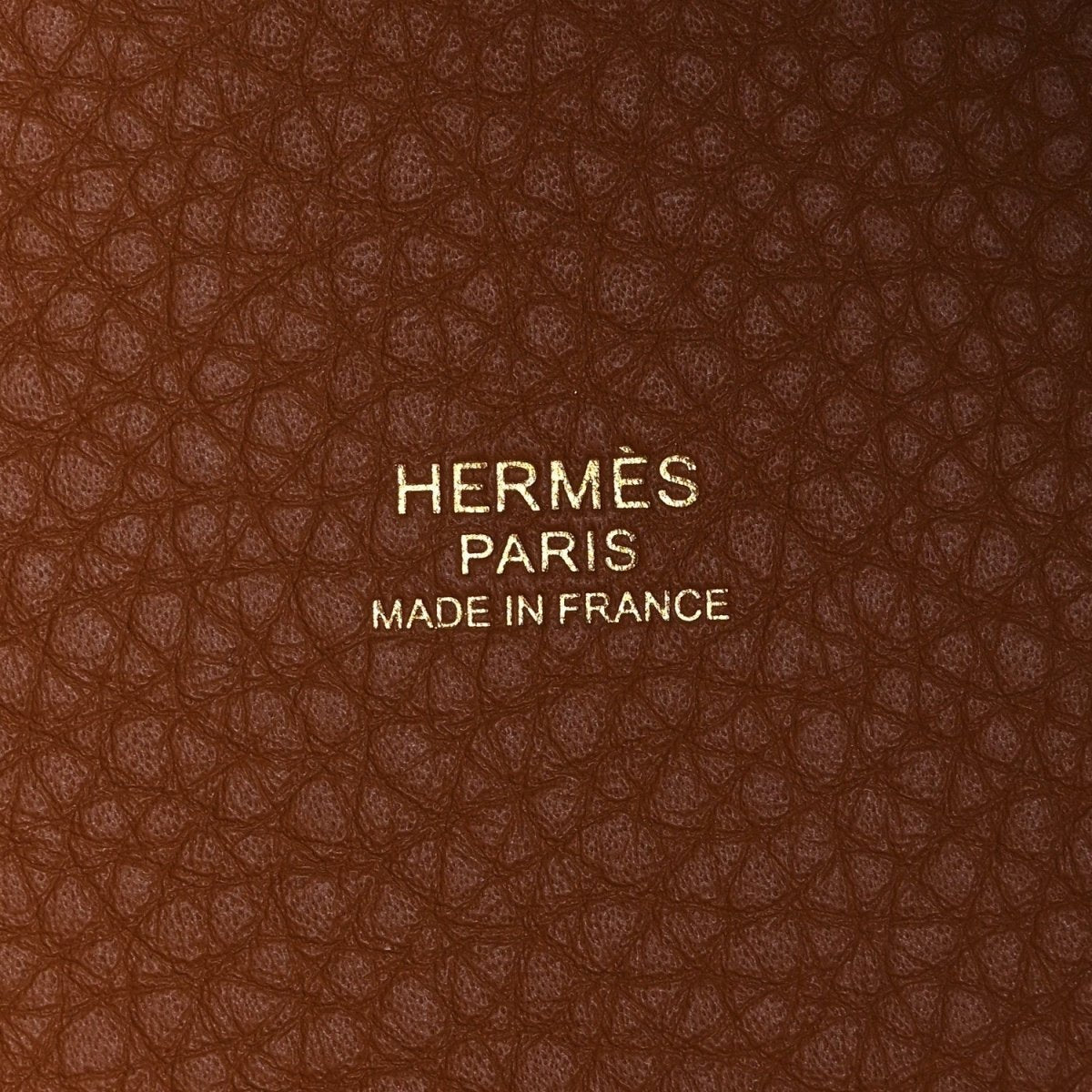 HERMES PARIS label on leather lining with MADE IN FRANCE text, brown textured leather.