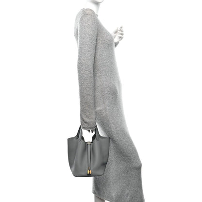 Grey leather tote bag held at the side with gold hardware and short handle