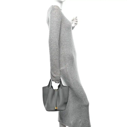 Grey leather tote bag held at the side with gold hardware and short handle