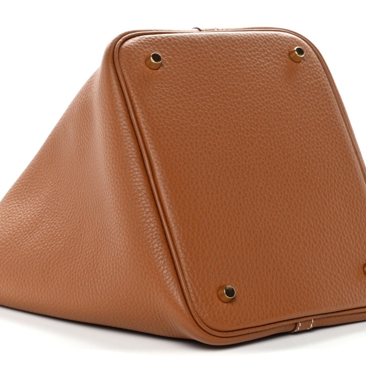 Tan leather bucket bag corner hardware and trapezoid shape with gold snaps