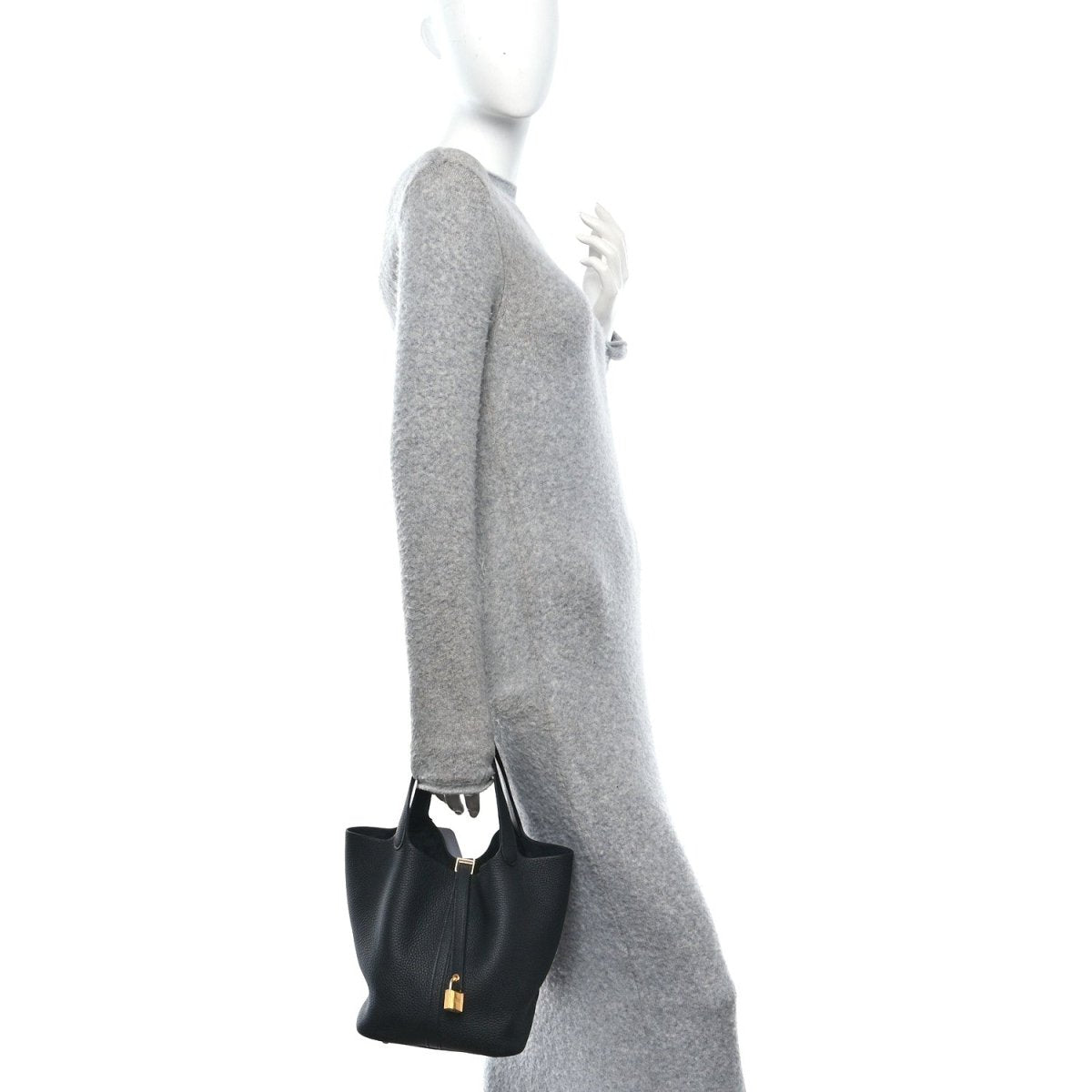 Black leather tote bag with central lock and short top handles, carried by hand.