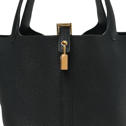 Close-up of black leather tote top with gold-tone lock and ring clasp hardware.