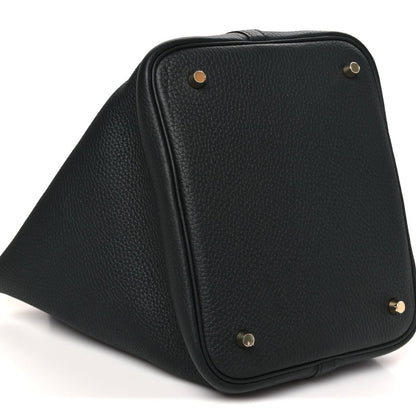 Black leather tote bag angled view with textured surface and gold-tone top hardware.