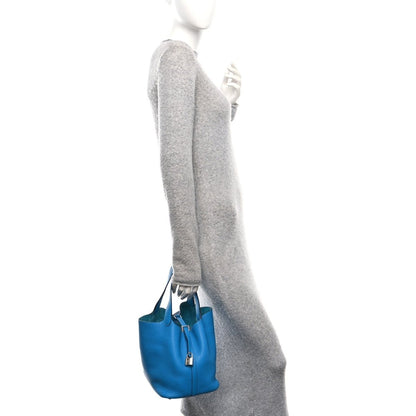 Blue leather mini tote bag with top handle and small lock clasp, shown at side