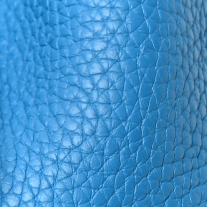 Blue pebbled leather close-up with crisscross texture and faint embossed text