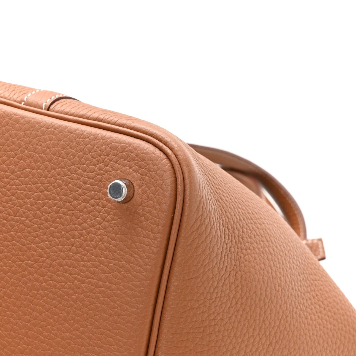 Tan pebbled leather tote corner with metal snap stud and top edge stitching