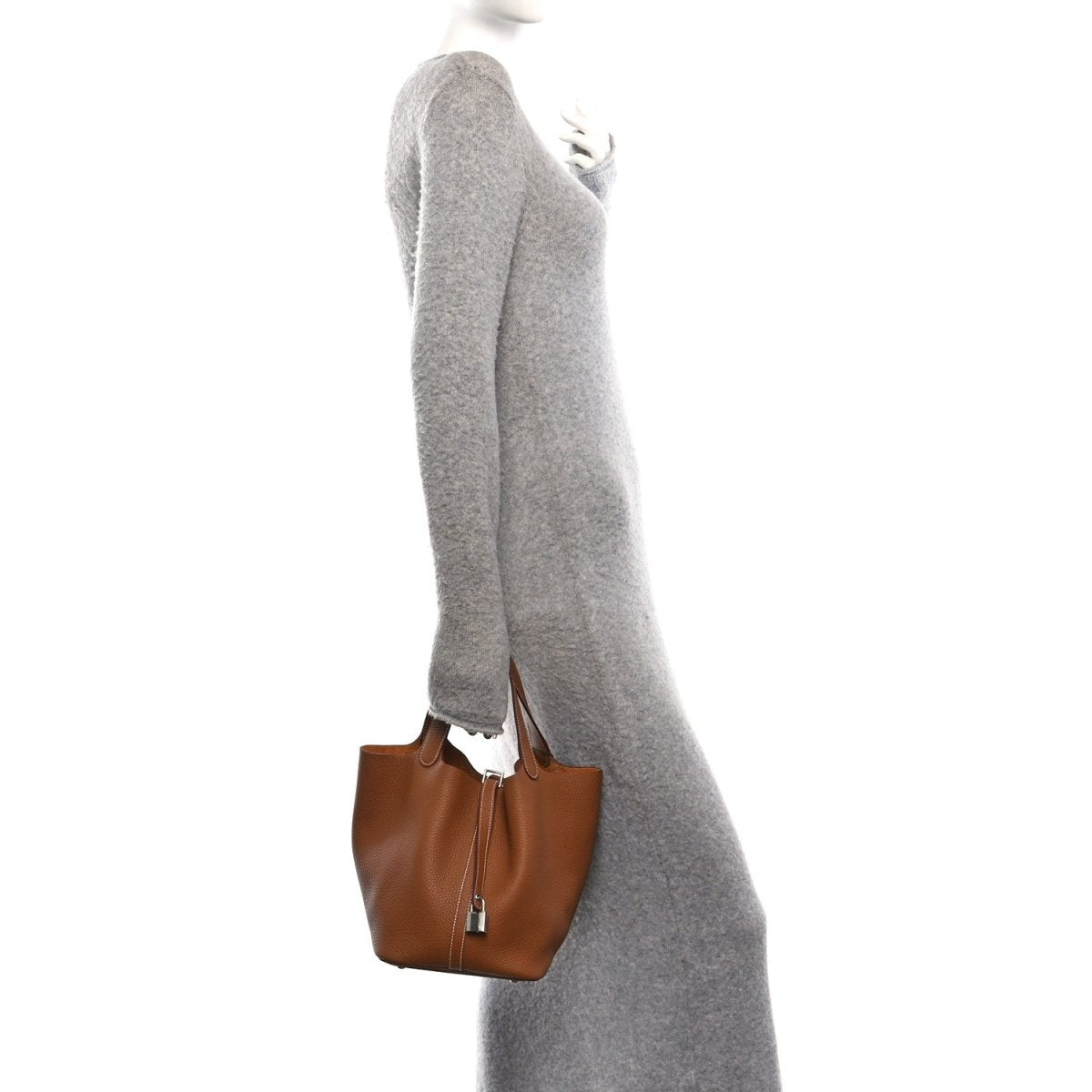 Tan leather mini tote hanging from a model’s side, with top handles and lock