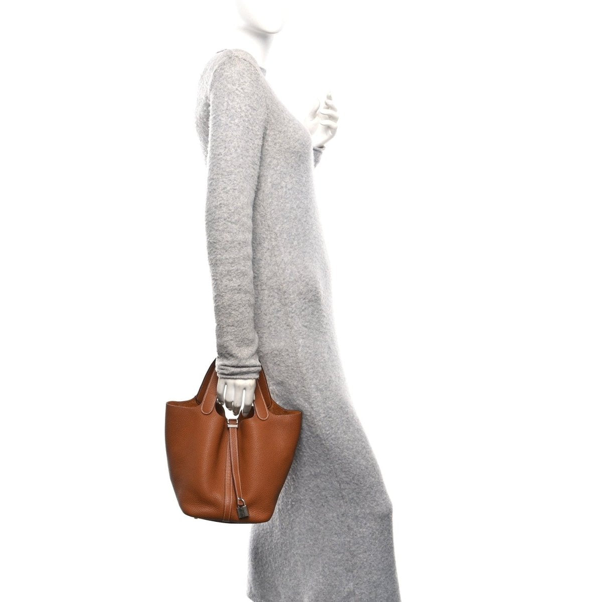 Golden brown leather mini tote on a wrist strap, worn by a person