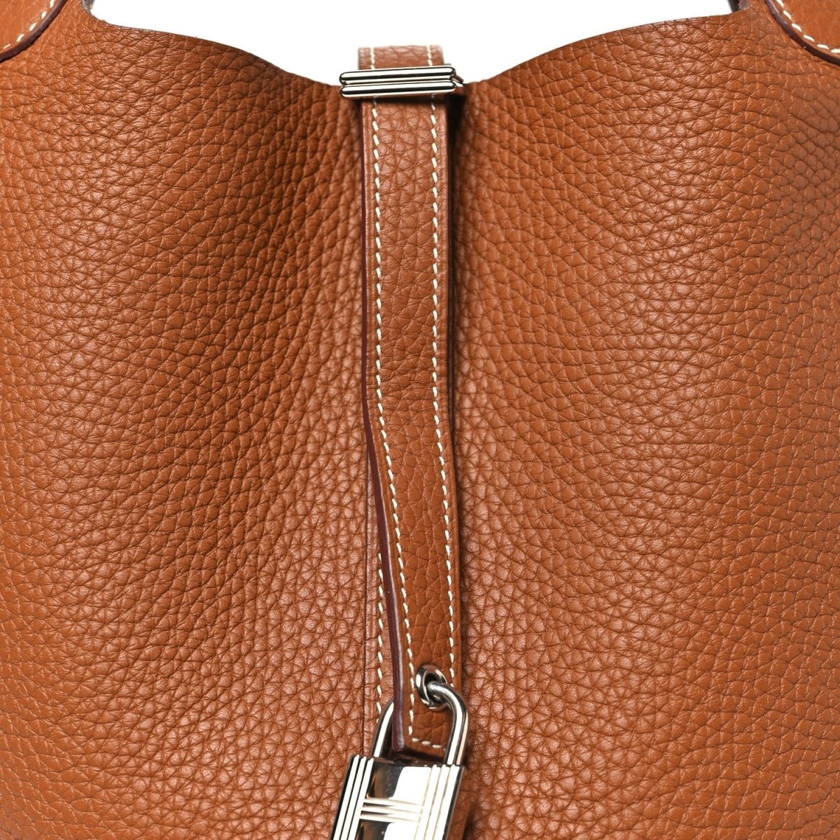 Golden brown leather tote bag close-up of zipper pull and metal hardware
