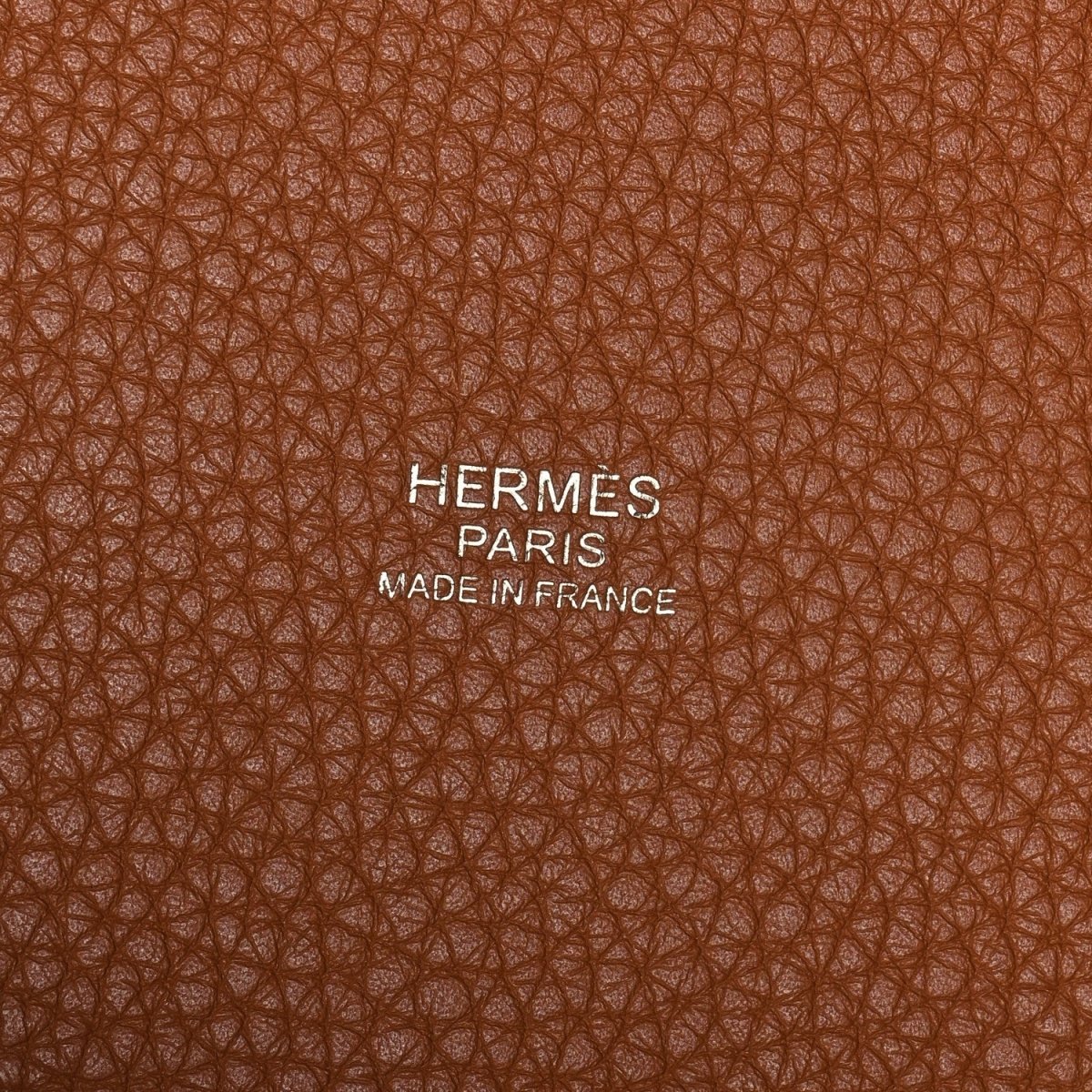 Golden brown leather tote bag exterior texture with Hermes Paris Made in France stamp