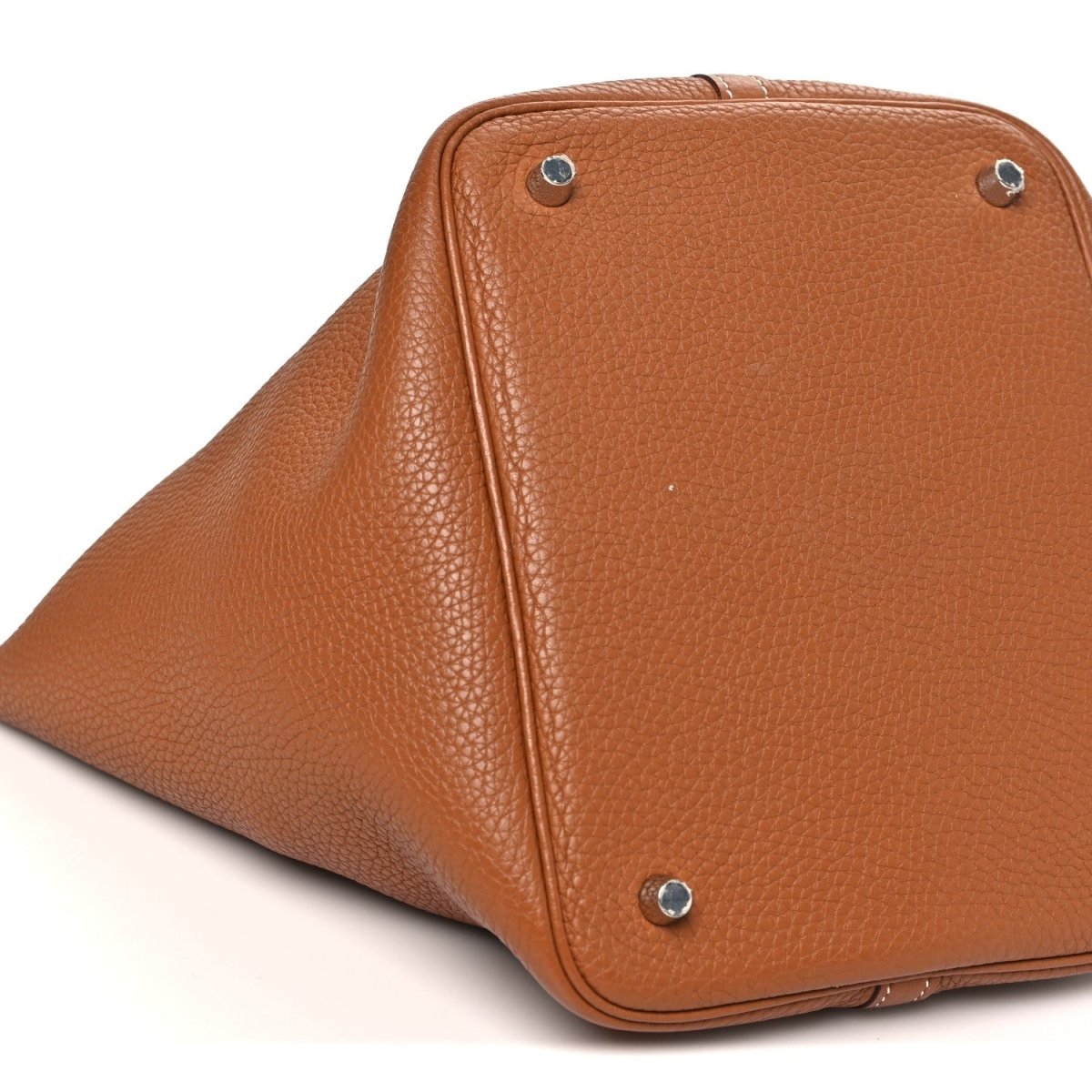Golden brown leather tote bag close-up of top corner with metal studs