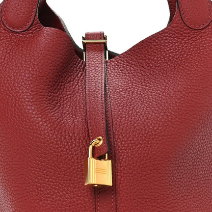 Red leather tote close-up of gold lock hardware and zipper strip