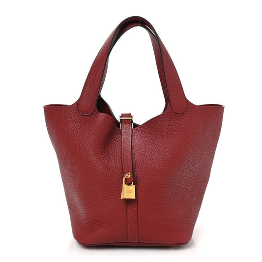 Red leather tote with top handles and central lock zipper closure, front view