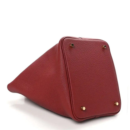 Red leather tote corner with gold hardware studs and curved side panel