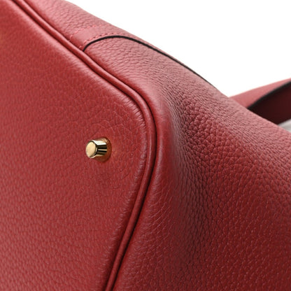 Red leather tote bag flap edge with gold clasp stud and textured grain