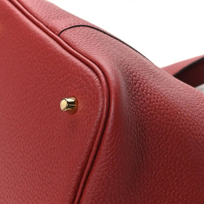 Red leather tote bag flap edge with gold clasp stud and textured grain