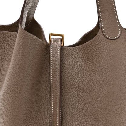 Taupe leather tote with gold lock clasp and contrast-stitched zipper