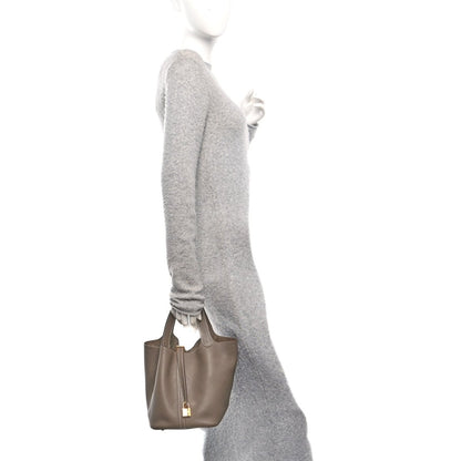 Taupe leather tote bag with gold lock, viewed from side
