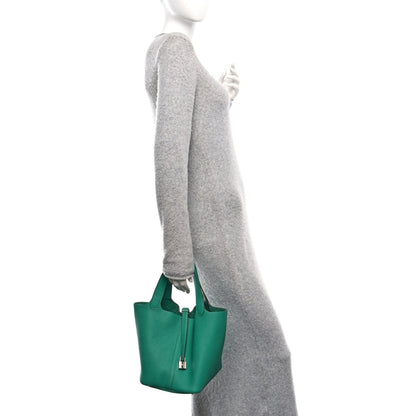 Green leather mini tote bag with top handles, worn on a shoulder