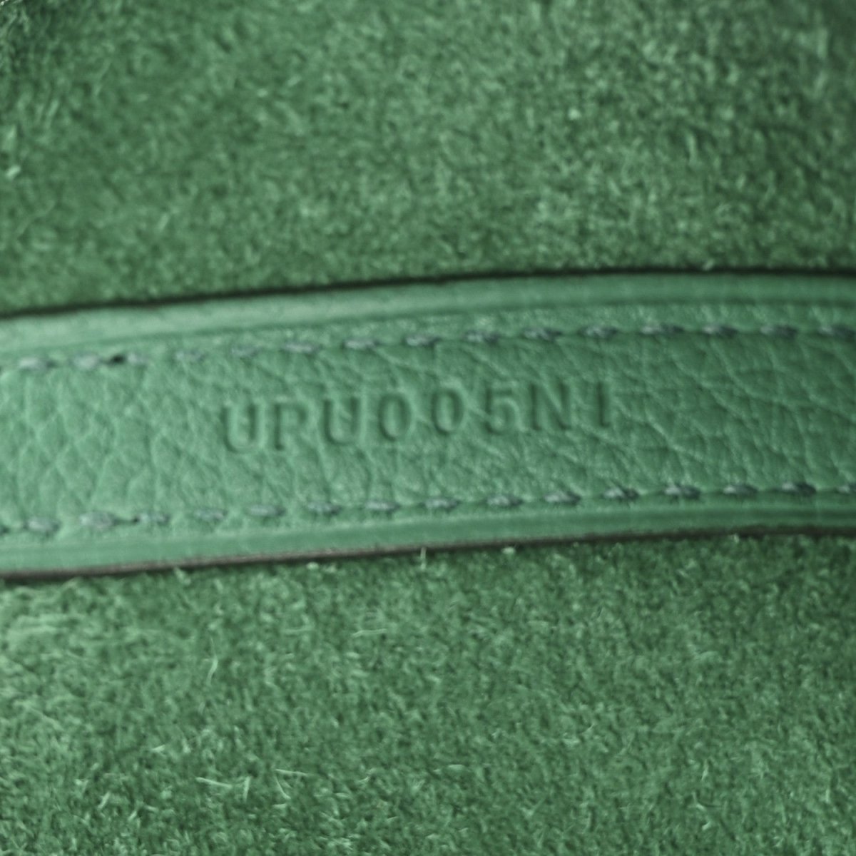 Close-up of green leather trim with embossed serial-style text